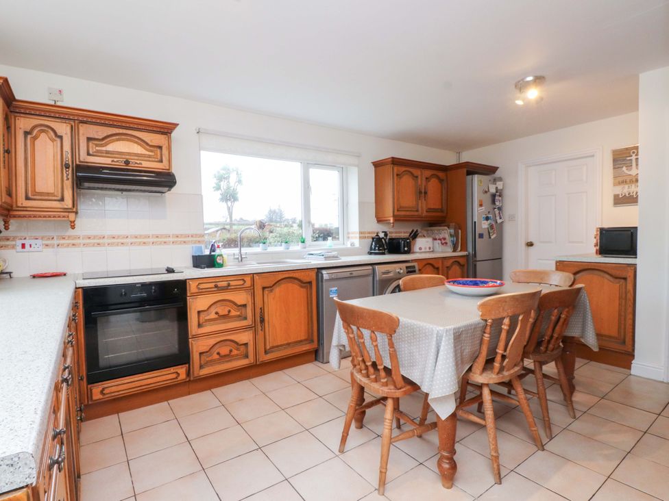 A kitchen with wooden cabinets and a table at Fernlea in Morfa Nefyn