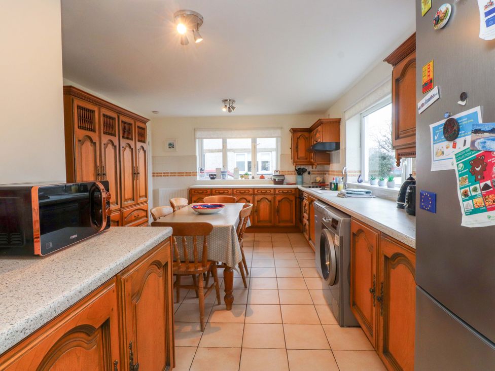 A kitchen with wooden cabinets and a table at Fernlea in Morfa Nefyn