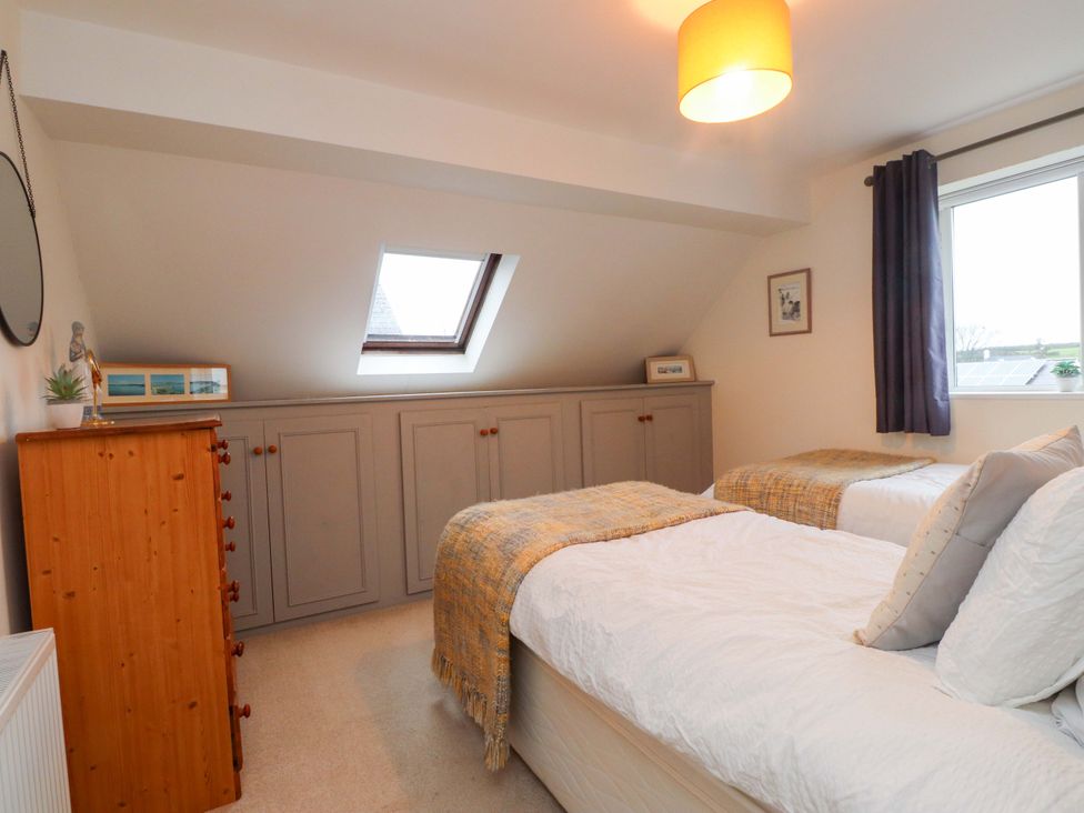 A bedroom with two beds and a window at Fernlea in Morfa Nefyn