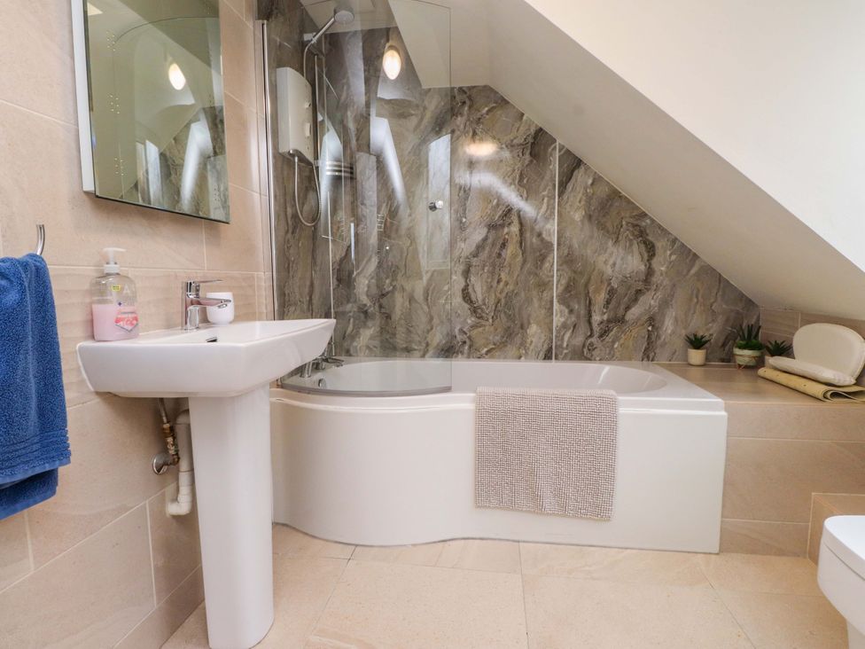 A bathroom with a bathtub and sink at Fernlea Morfa Nefyn