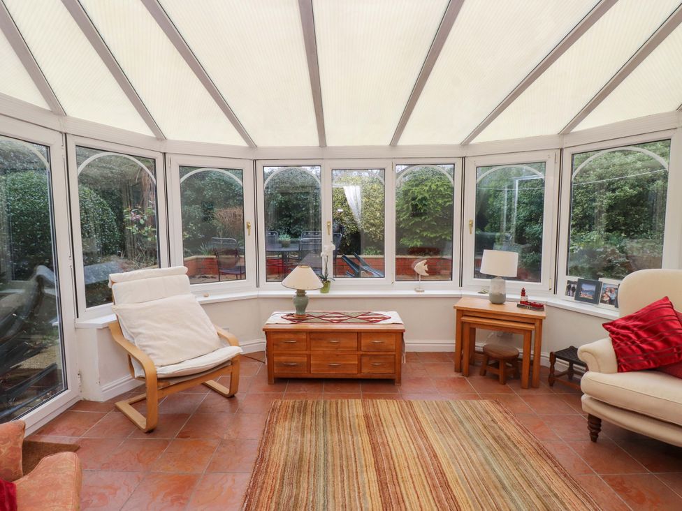 A conservatory with seating and a table at Fernlea in Morfa Nefyn
