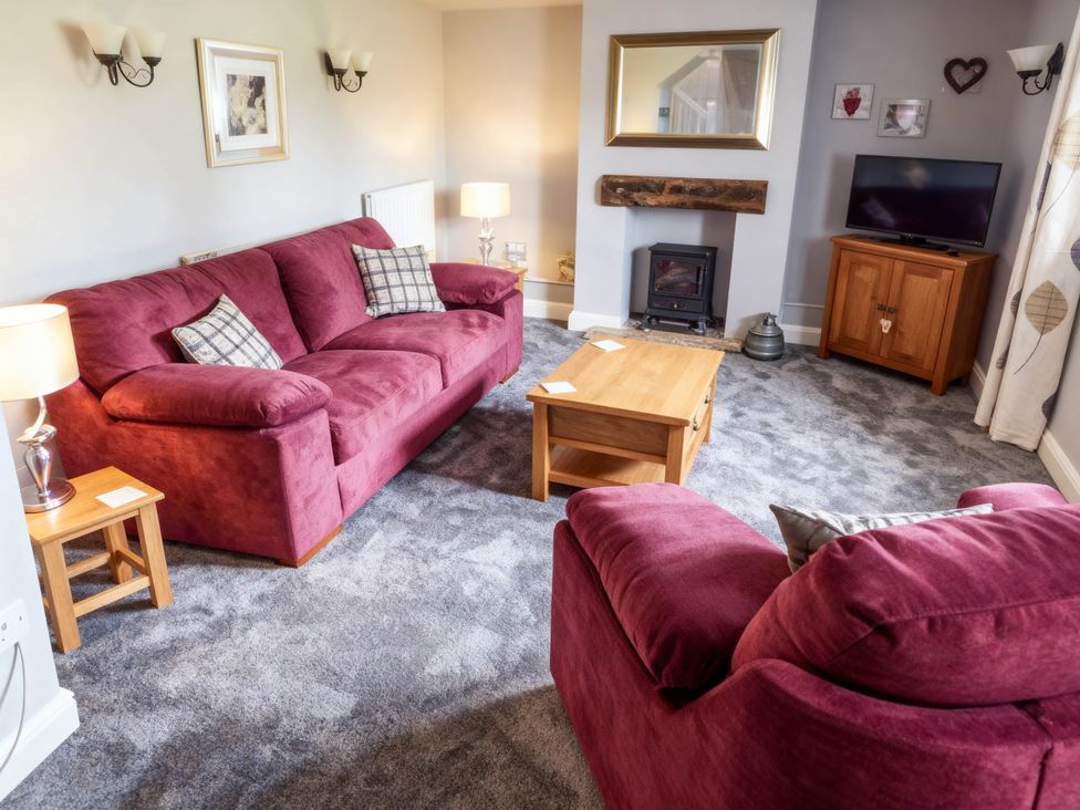 A living room with sofa, armchair, coffee table and television at Little Owl Barn Longnor