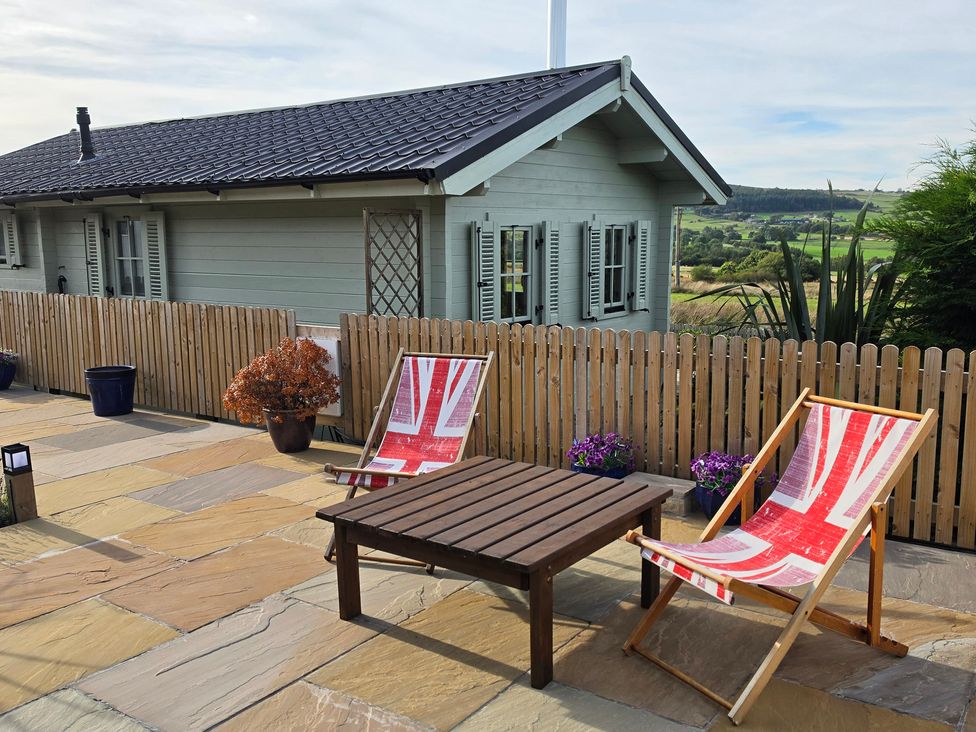 An outdoor area with deck chairs and a wooden table at The Shooting Lodge Longnor