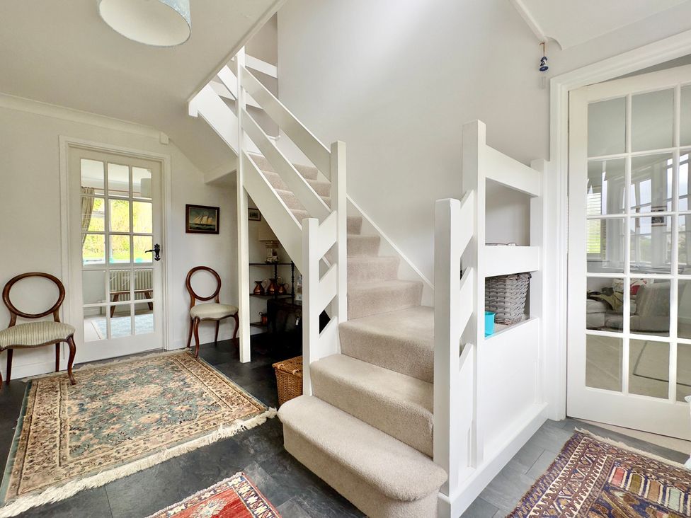A hallway with stairs and chairs at Kilcarreg in Rock near Wadebridge