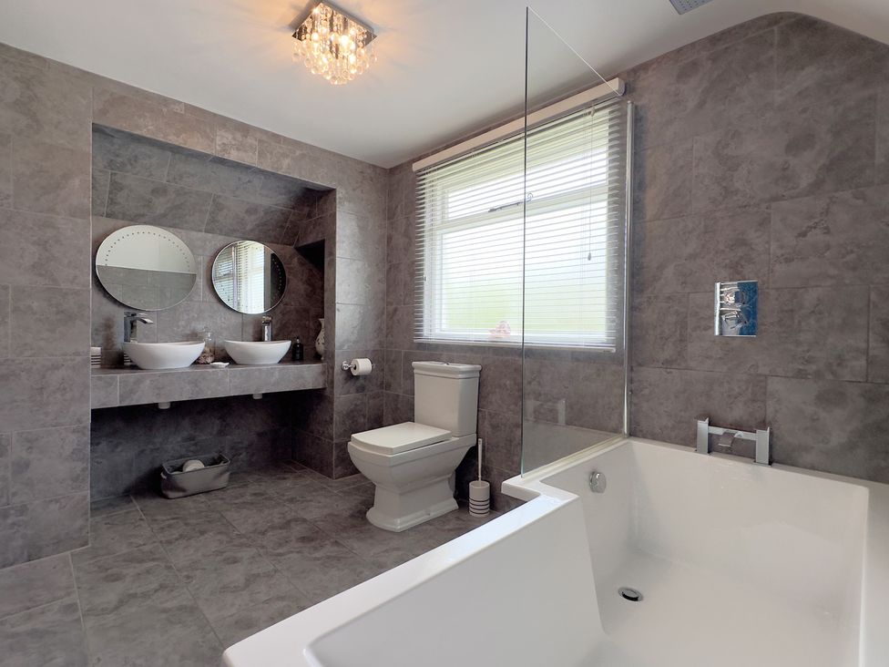A bathroom with a bathtub, sink, toilet, and mirrors at Kilcarreg near Rock and Wadebridge