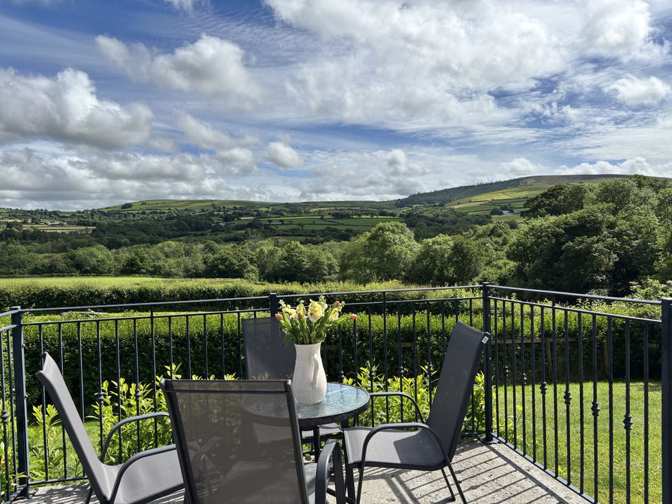 A balcony with table and chairs overlooking hills at Llaethdy - The Dairy Boncath near Crymych