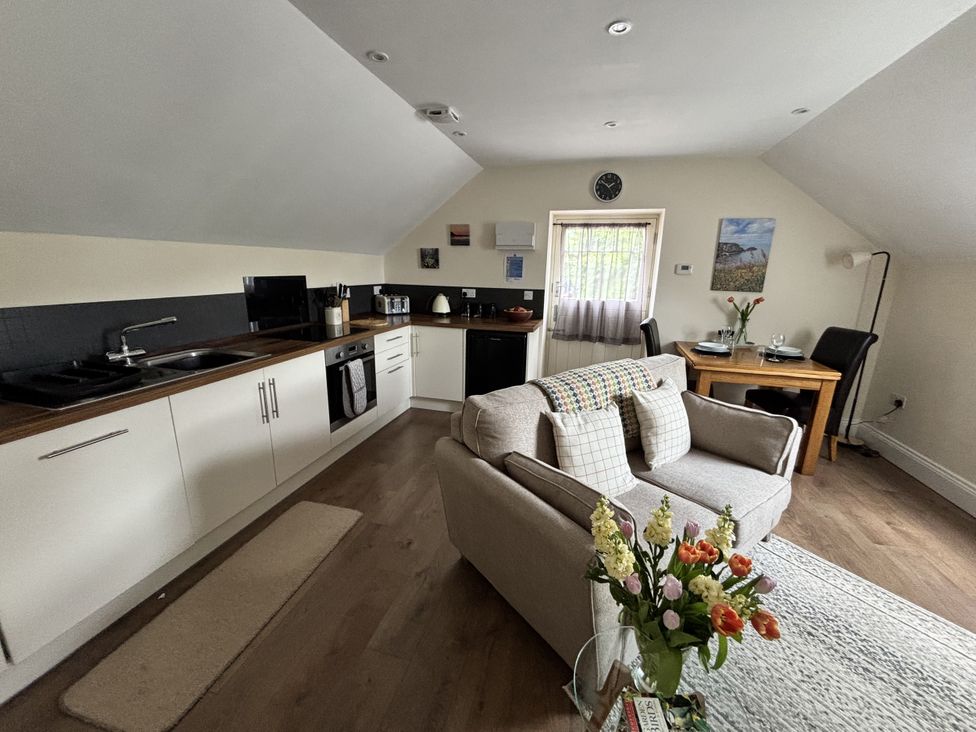 A kitchen with a sofa and dining table at Lloft Gwair - Hayloft Boncath near Crymych