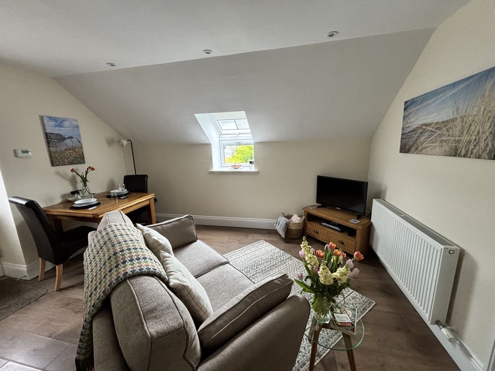 A living room with a sofa and dining table at Lloft Gwair - Hayloft Boncath near Crymych