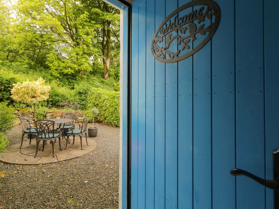 A garden with a table and chairs viewed through a blue door at Rosslare Cottage Broughshane