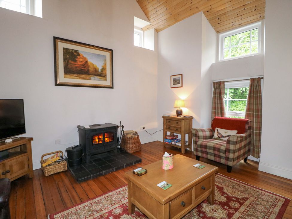 A living room with a fireplace and television at Rosslare Cottage in Broughshane