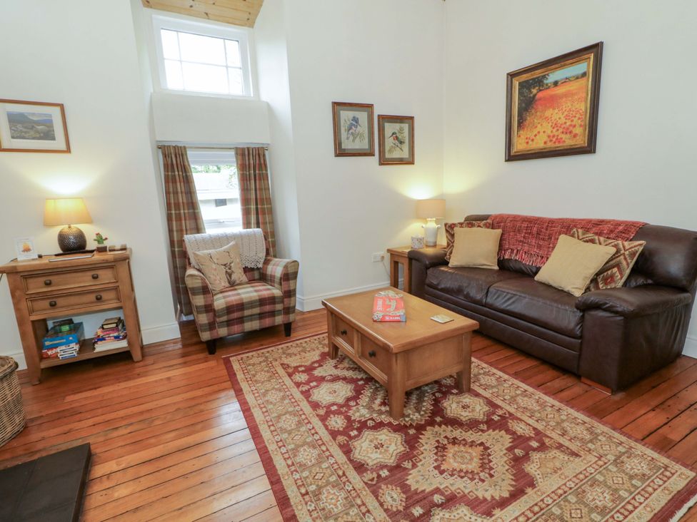 A living room with a sofa and armchair at Rosslare Cottage in Broughshane