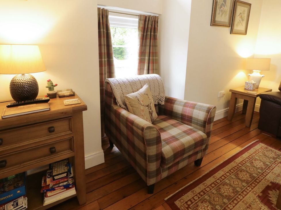 A living room with an armchair and a lamp at Rosslare Cottage Broughshane