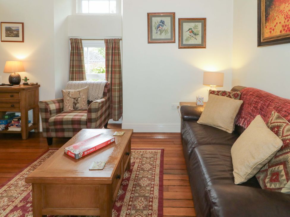 A living room with a sofa and armchair at Rosslare Cottage in Broughshane