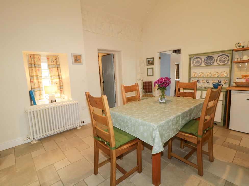 A dining room with a table and chairs at Rosslare Cottage in Broughshane