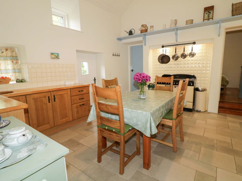 A kitchen with a dining table and chairs at Rosslare Cottage Broughshane
