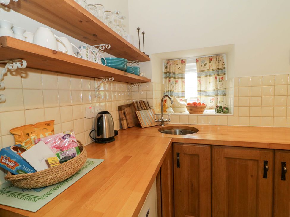 A kitchen with wooden shelves and a sink at Rosslare Cottage in Broughshane