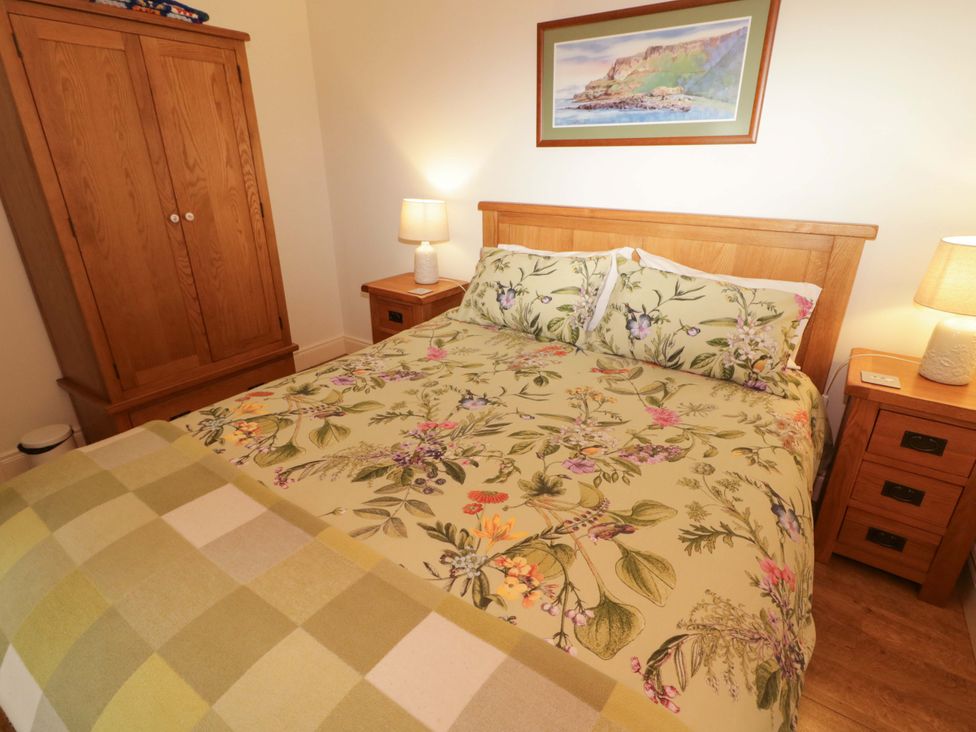 A bedroom with a bed and wardrobe at Rosslare Cottage Broughshane