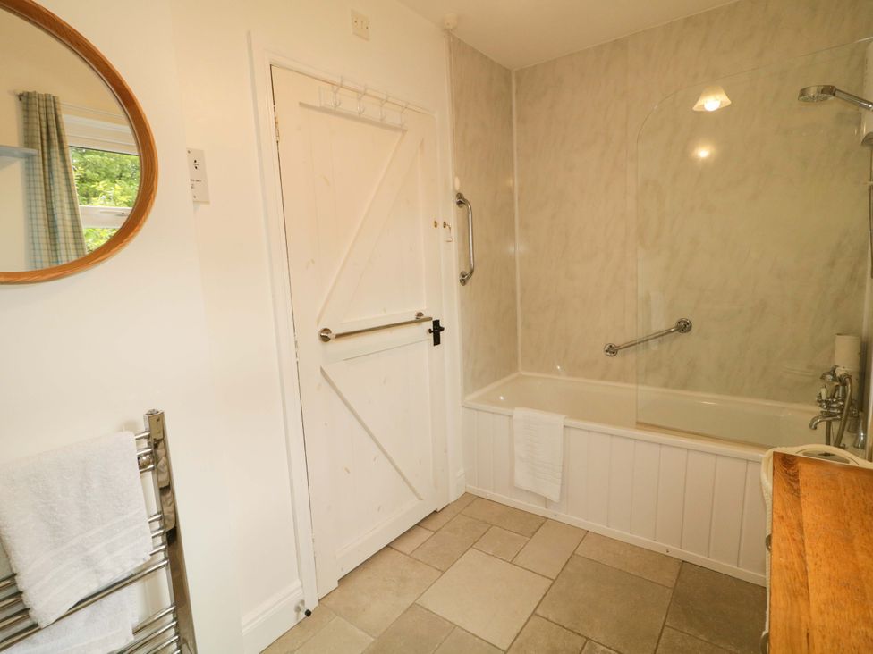 A bathroom featuring a bath tub and a towel rail at Rosslare Cottage in Broughshane