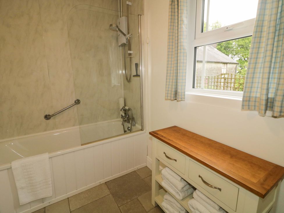 A bathroom with a bathtub and shower at Rosslare Cottage in Broughshane