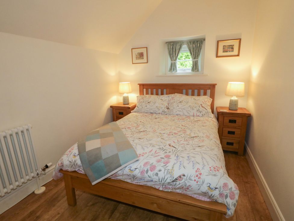 A bedroom with a bed and bedside tables at Rosslare Cottage Broughshane