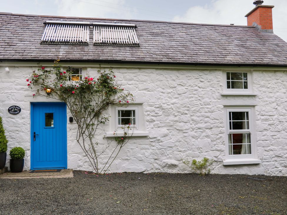 A cottage with a blue door and windows at Rosslare Cottage Broughshane