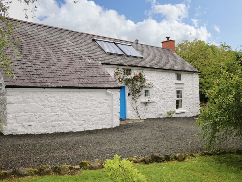 A cottage with a blue door and solar panels at Rosslare Cottage in Broughshane