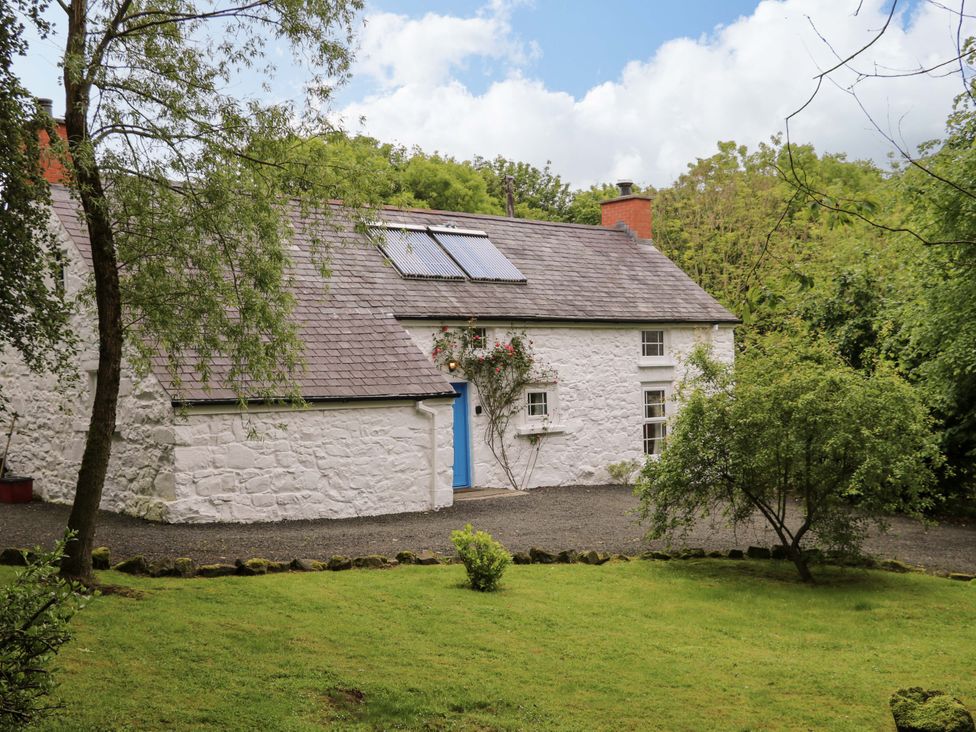 A cottage with a garden and trees at Rosslare Cottage in Broughshane