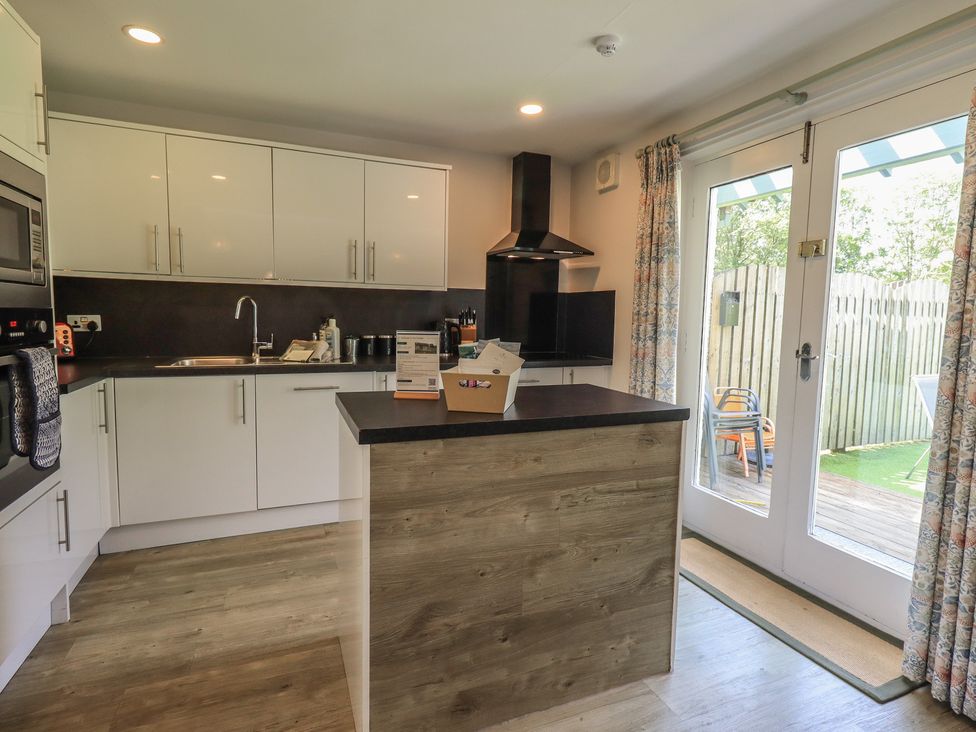 A kitchen with modern appliances and a door leading to a deck at Yew - Woodland Cottages in Bowness-On-Windermere