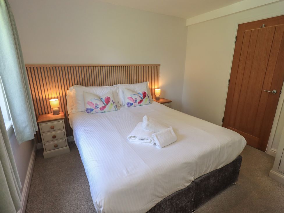 A bedroom with bed and bedside table at Yew - Woodland Cottages in Bowness-On-Windermere