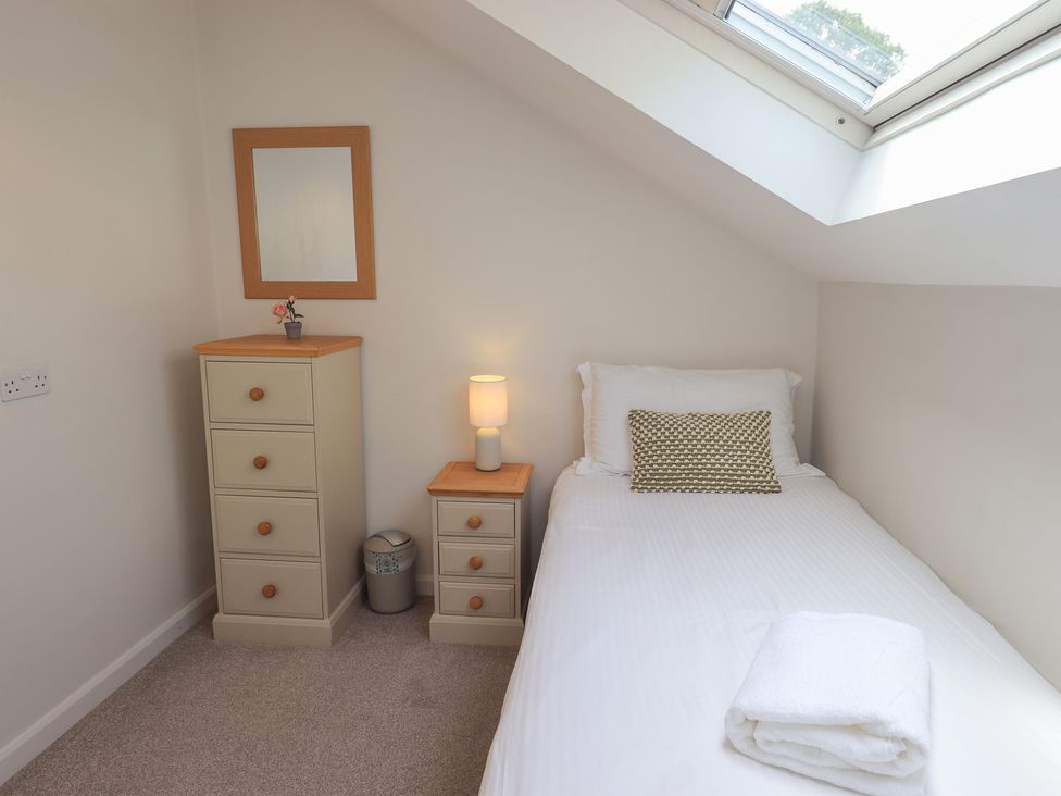 A bedroom with a single bed and dresser at Yew - Woodland Cottages Bowness-On-Windermere
