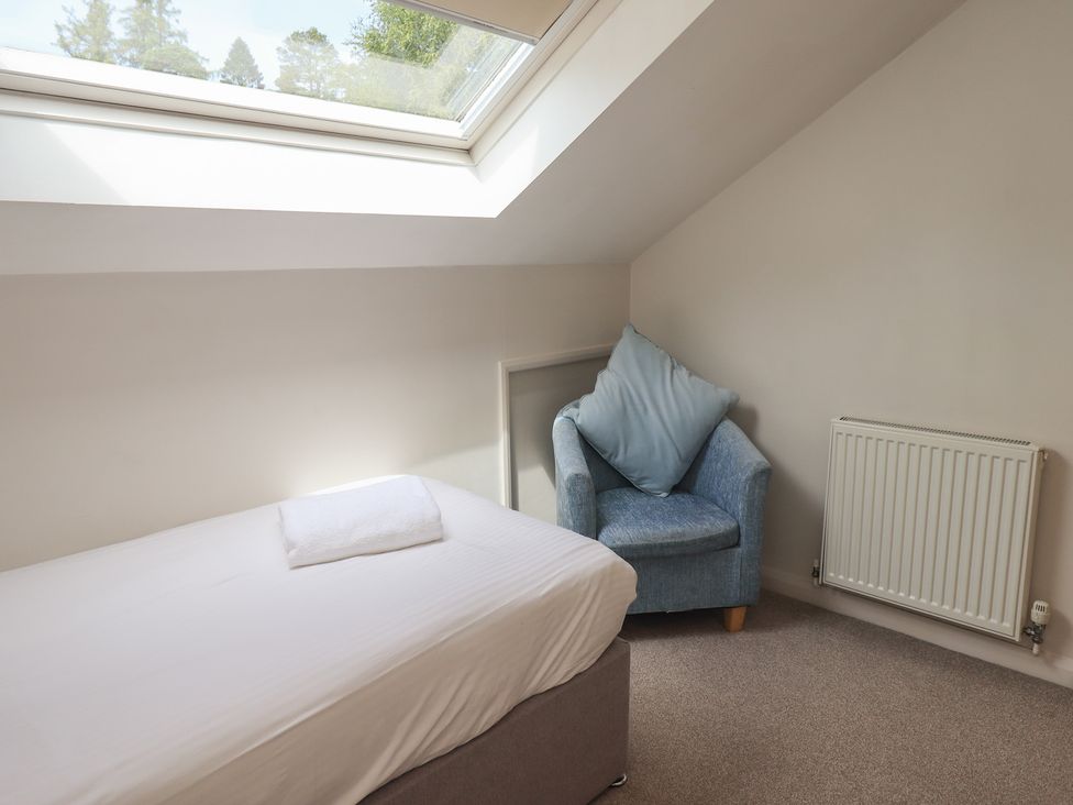 A bedroom with a bed and armchair at Yew - Woodland Cottages, Bowness-On-Windermere