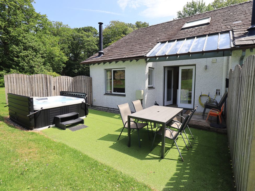 An outdoor area with a hot tub and dining table at Yew - Woodland Cottages Bowness-On-Windermere