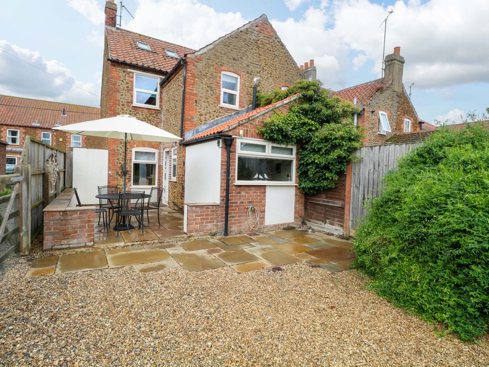 A garden with patio furniture and greenery at Fern Cottage in Heacham