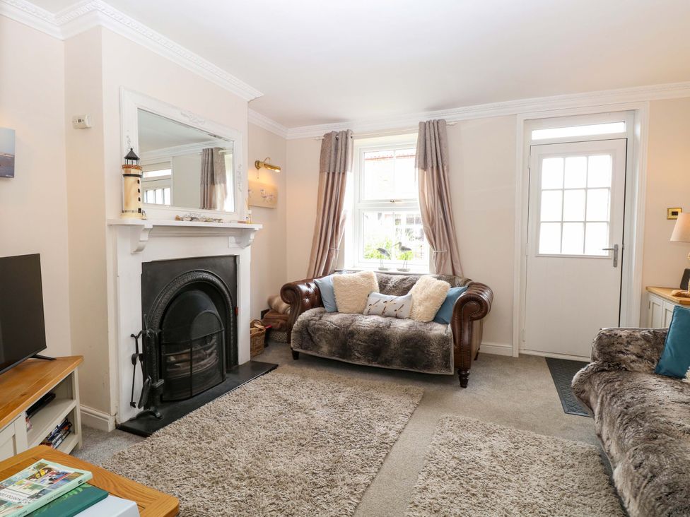 A living room with a fireplace and a television at Fern Cottage in Heacham
