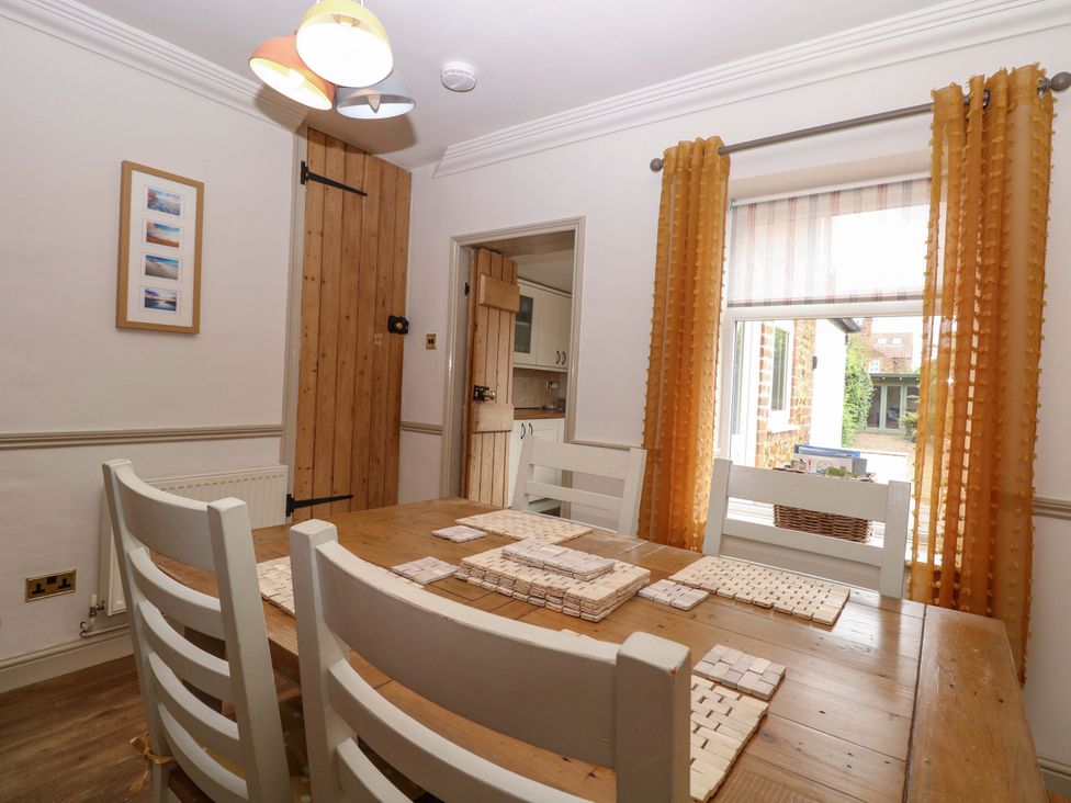 A dining room with a wooden table and chairs at Fern Cottage in Heacham