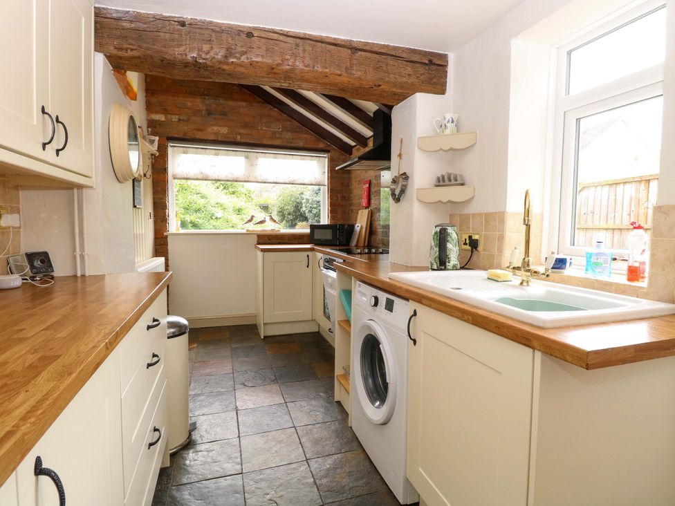 A kitchen with a wooden countertop and a washing machine at Fern Cottage in Heacham