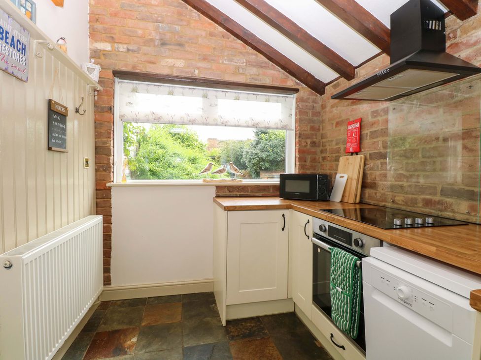 A kitchen with appliances and a window at Fern Cottage Heacham