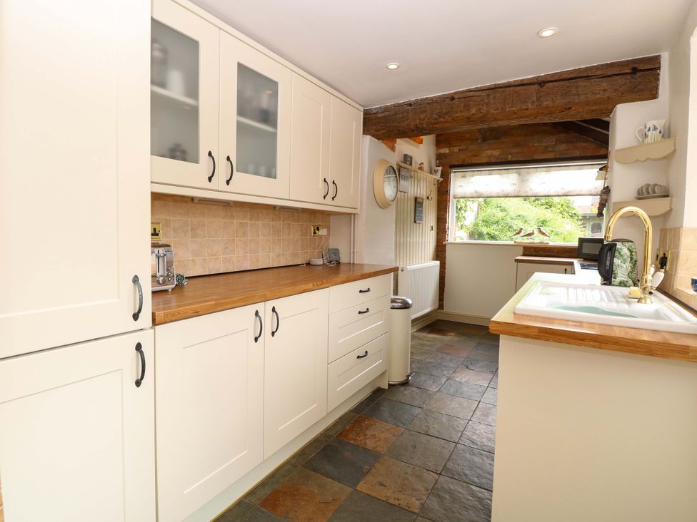A kitchen with cabinets and appliances at Fern Cottage Heacham