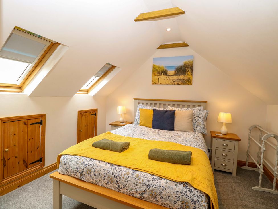 A bedroom with a bed and skylights at Fern Cottage in Heacham