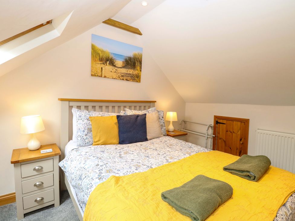 A bedroom with a bed and nightstand at Fern Cottage in Heacham