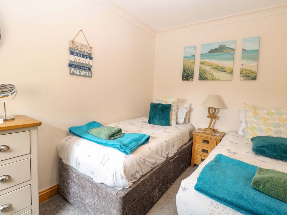 A bedroom with two beds and a bedside table at Fern Cottage Heacham