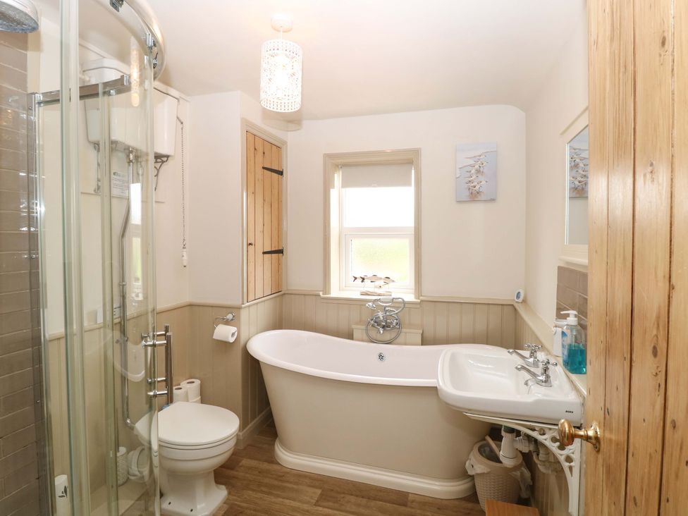 A bathroom with a bathtub, toilet, and sink at Fern Cottage in Heacham