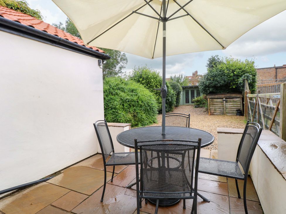 A garden with a table and chairs under an umbrella at Fern Cottage in Heacham