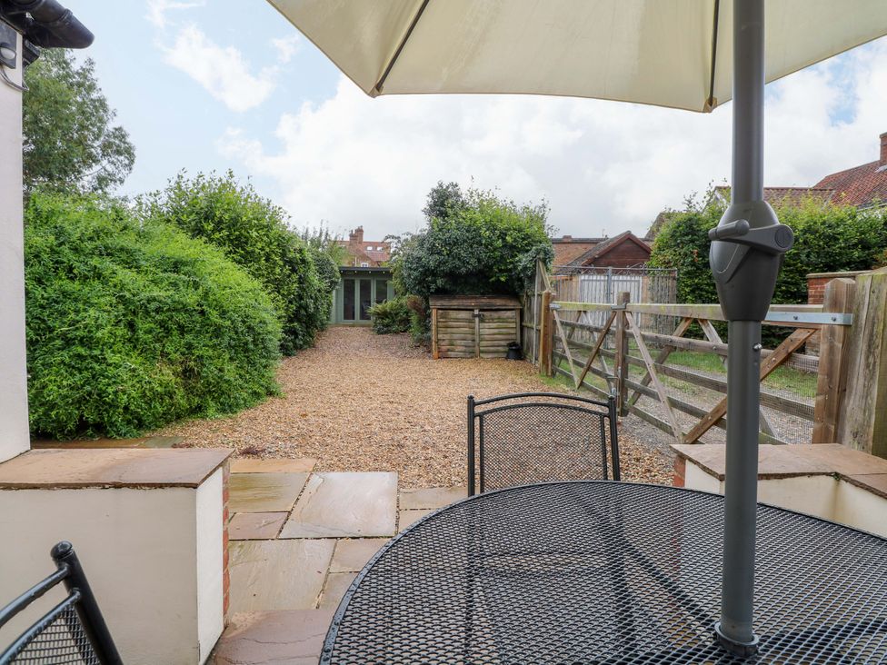 A garden with a table and chairs under an umbrella at Fern Cottage in Heacham