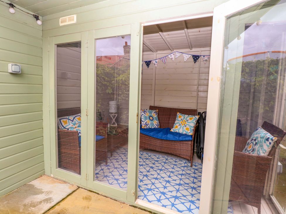 A garden room with wicker furniture and bunting at Fern Cottage in Heacham