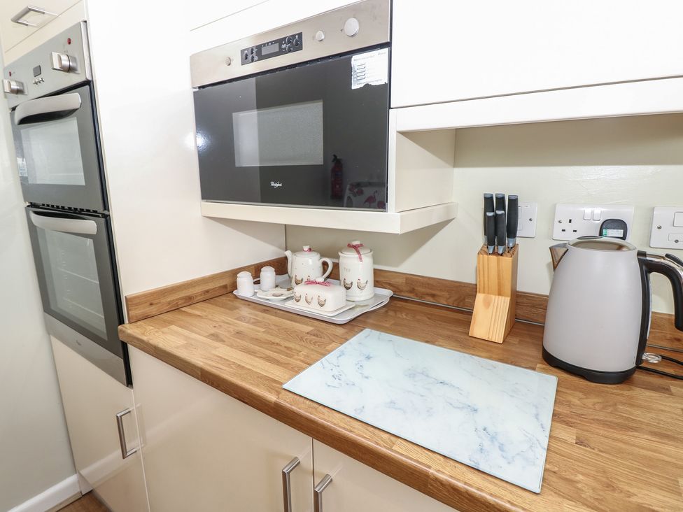 A kitchen with an oven, microwave, kettle, knife block, and tea set at Roebeck Retreat in Ryde