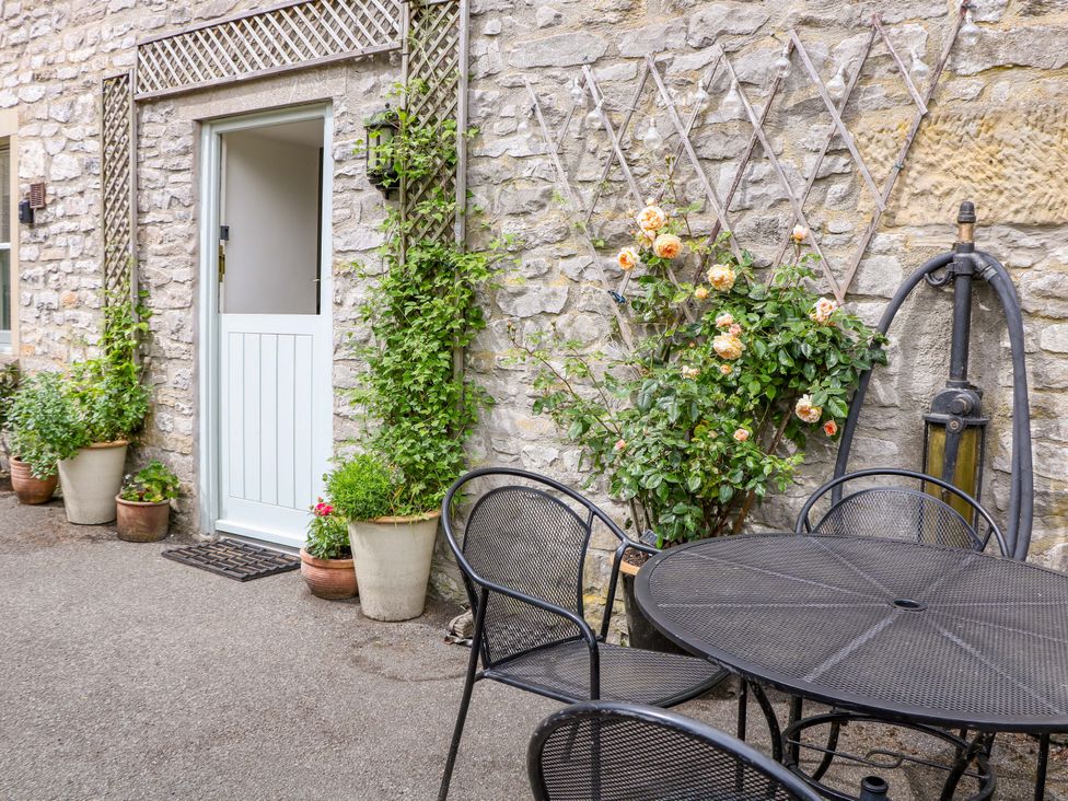 An outdoor area with a stone wall, table, and plants at Brookside Barn in Bradwell