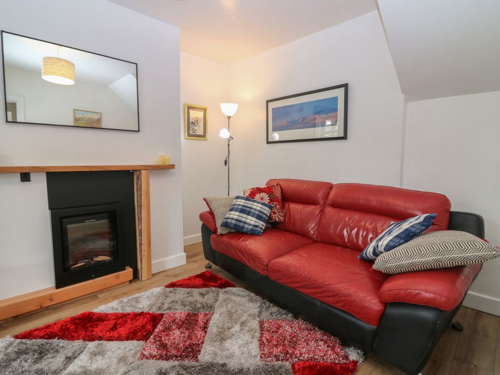 A living room with a red sofa and fireplace at Alt na Voir in Tomintoul