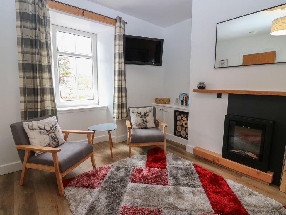 A sitting room with two armchairs and a fireplace at Alt na Voir in Tomintoul