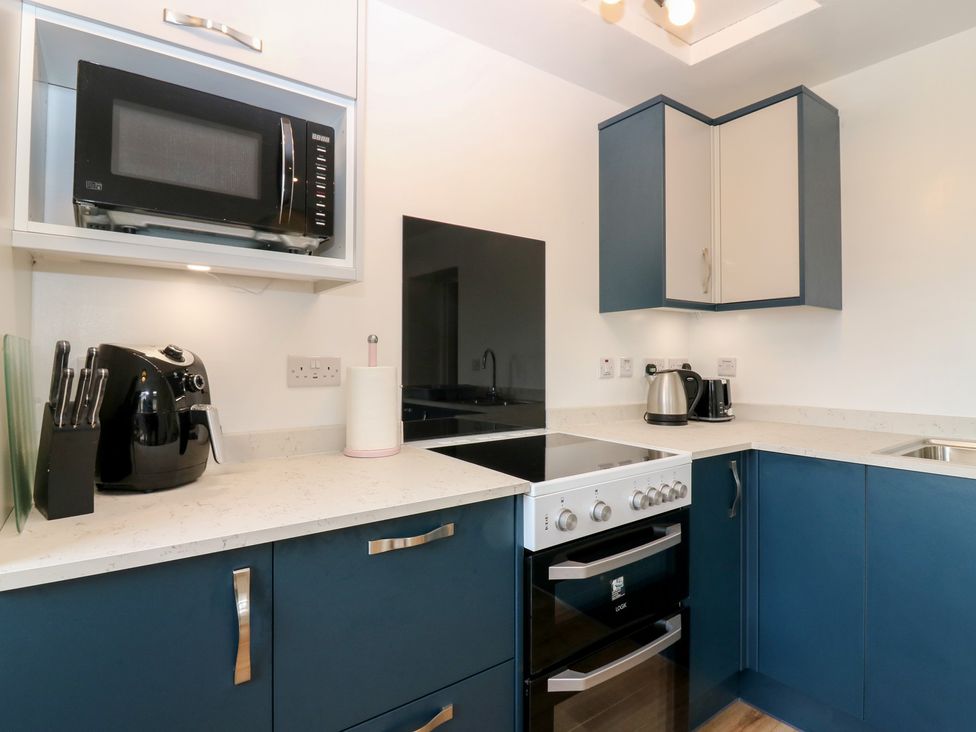 A kitchen with a microwave, cooker, and air fryer at Alt na Voir, Tomintoul